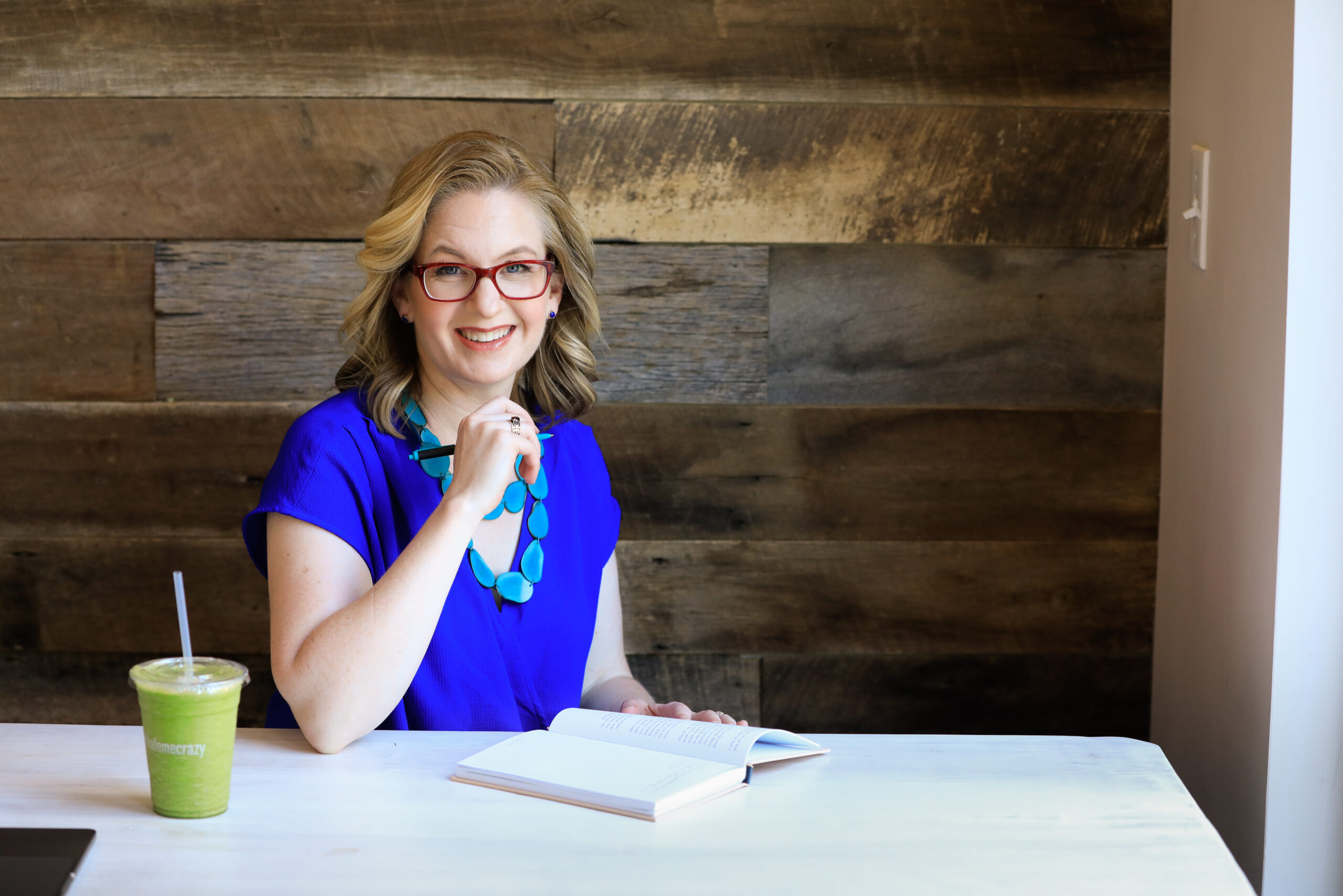 Erin sitting at a table holding a pen and with a notebook in front of her.